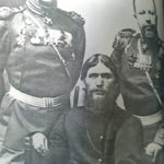 Rasputin sentado com ministros russos de pé ao seu lado